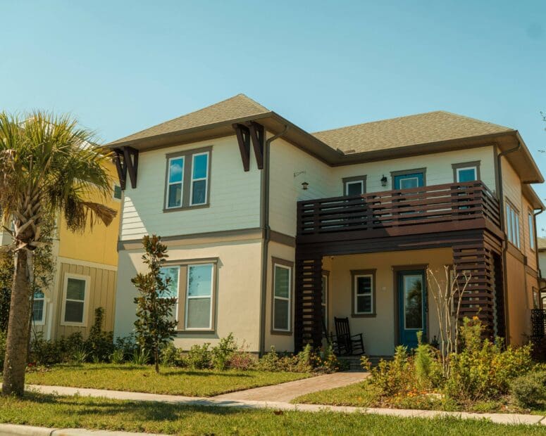 A contemporary two-story house in Orlando that's beige with brown trim. There is a second-story deck and a palm tree in the front yard.