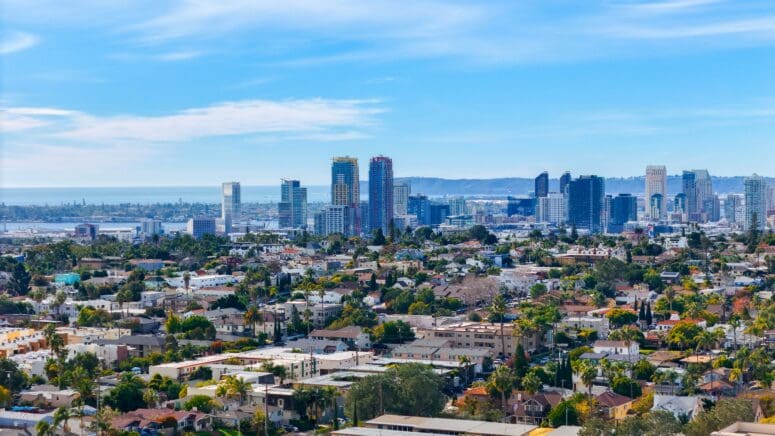 Drone shot of San Diego, showing the buildings downtown and the ocean and hillsides beyond.