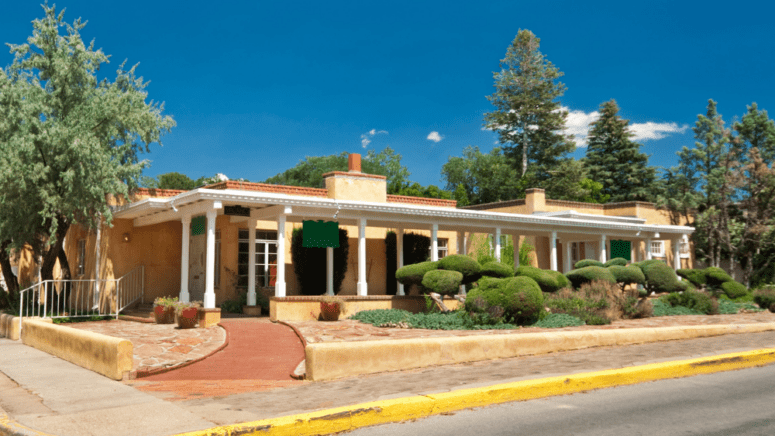 An image of a house listed for sale, with the owner looking up the cost to sell a home in New Mexico
